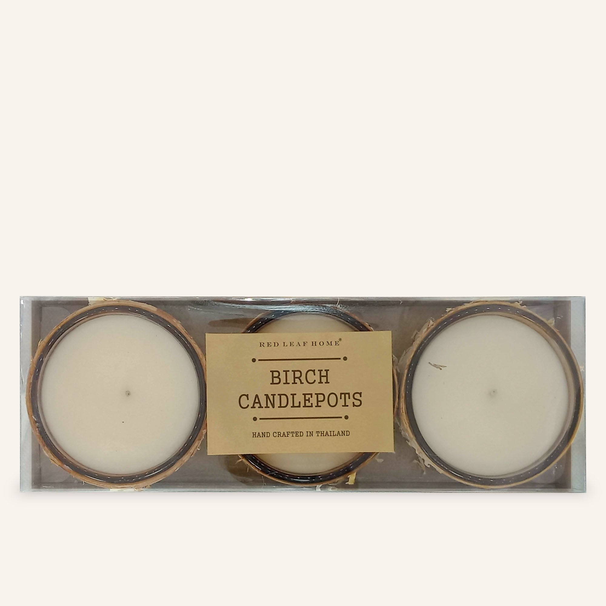 A pack of 3 birch filled candles from over head. There is a brown label that reads, "Red Leaf Home. Birch Candlepots. Handcrafted in Thailand."