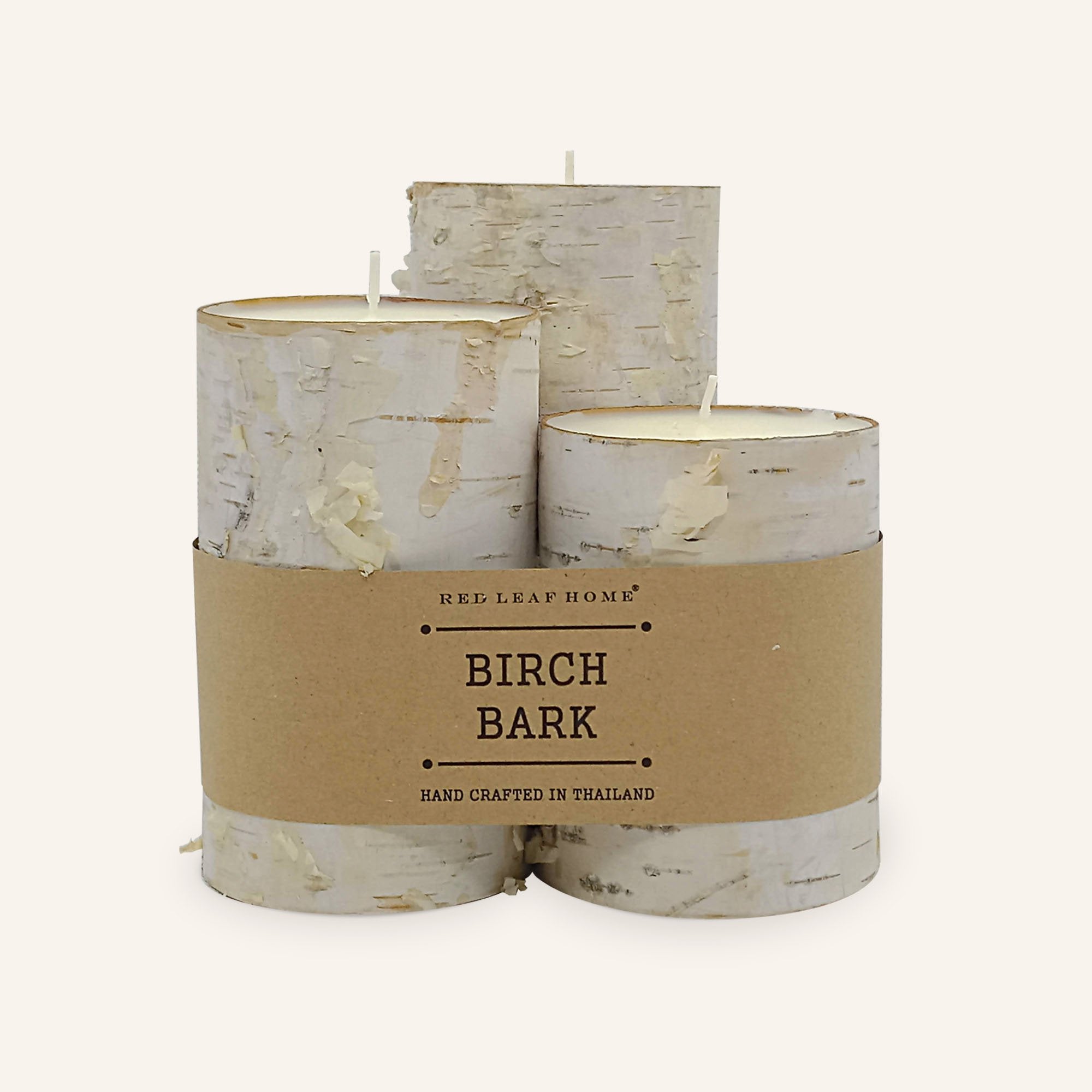 Three Birch-bark candles rapped in a brown paper label that reads, "Red Leaf Home. Birch Bark. Hand crafted in Thailand."